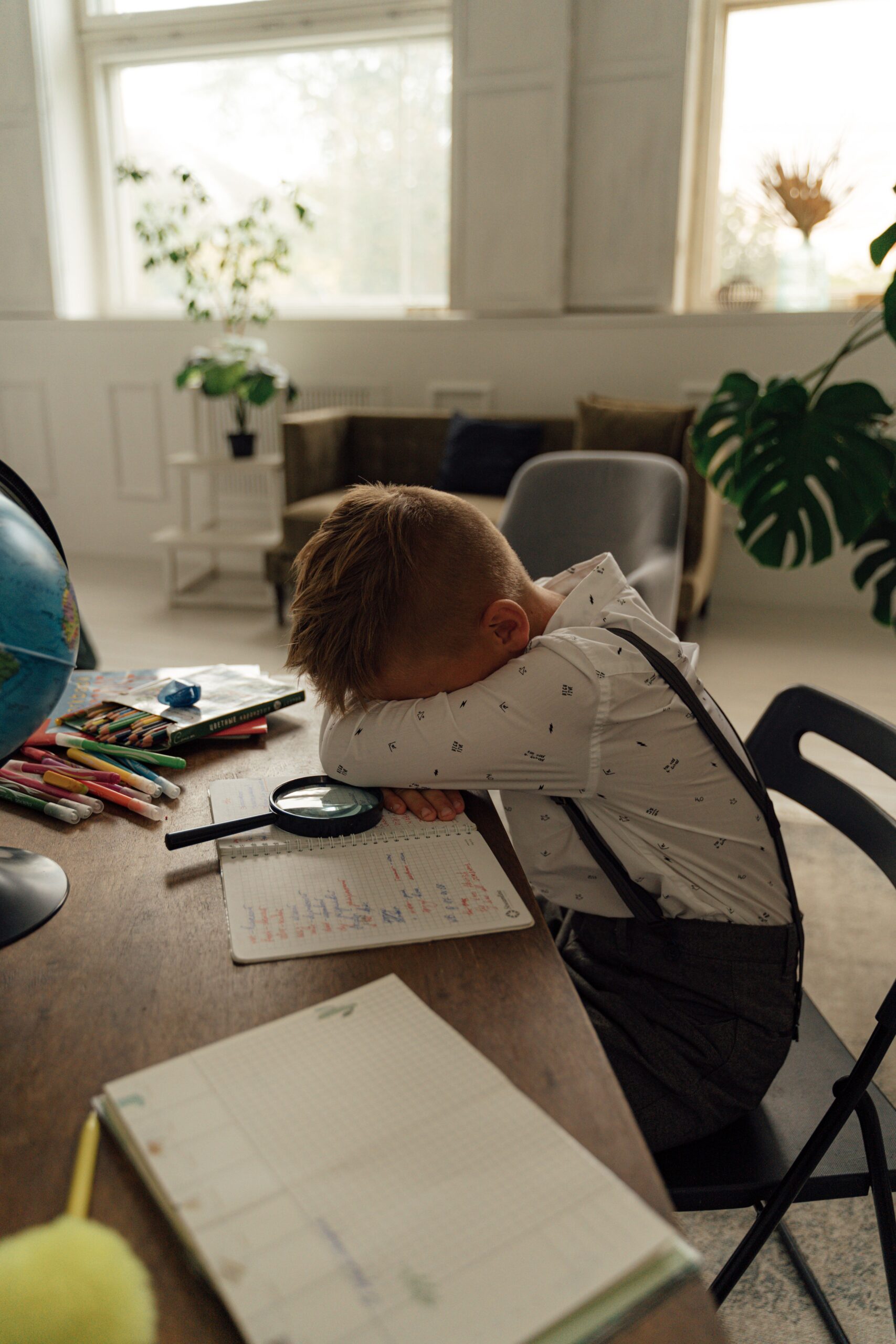 Enfant fatigué, tête posée sur son cahier de devoirs