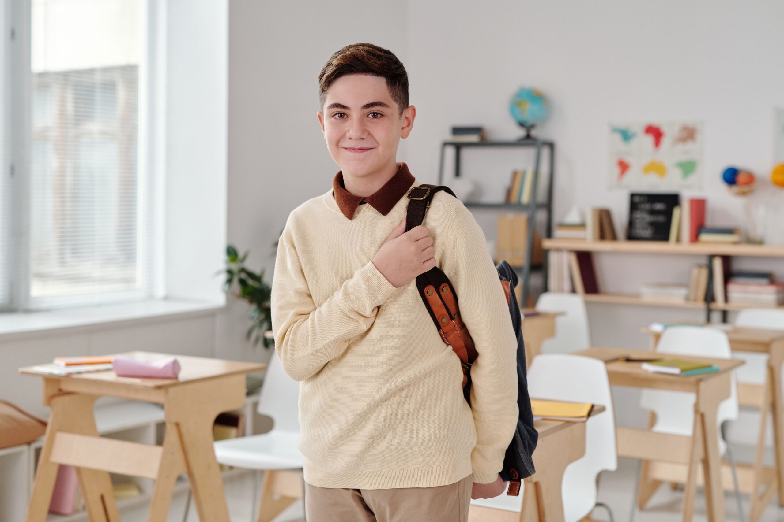 Collégien souriant avec son sac à dos en salle de classe