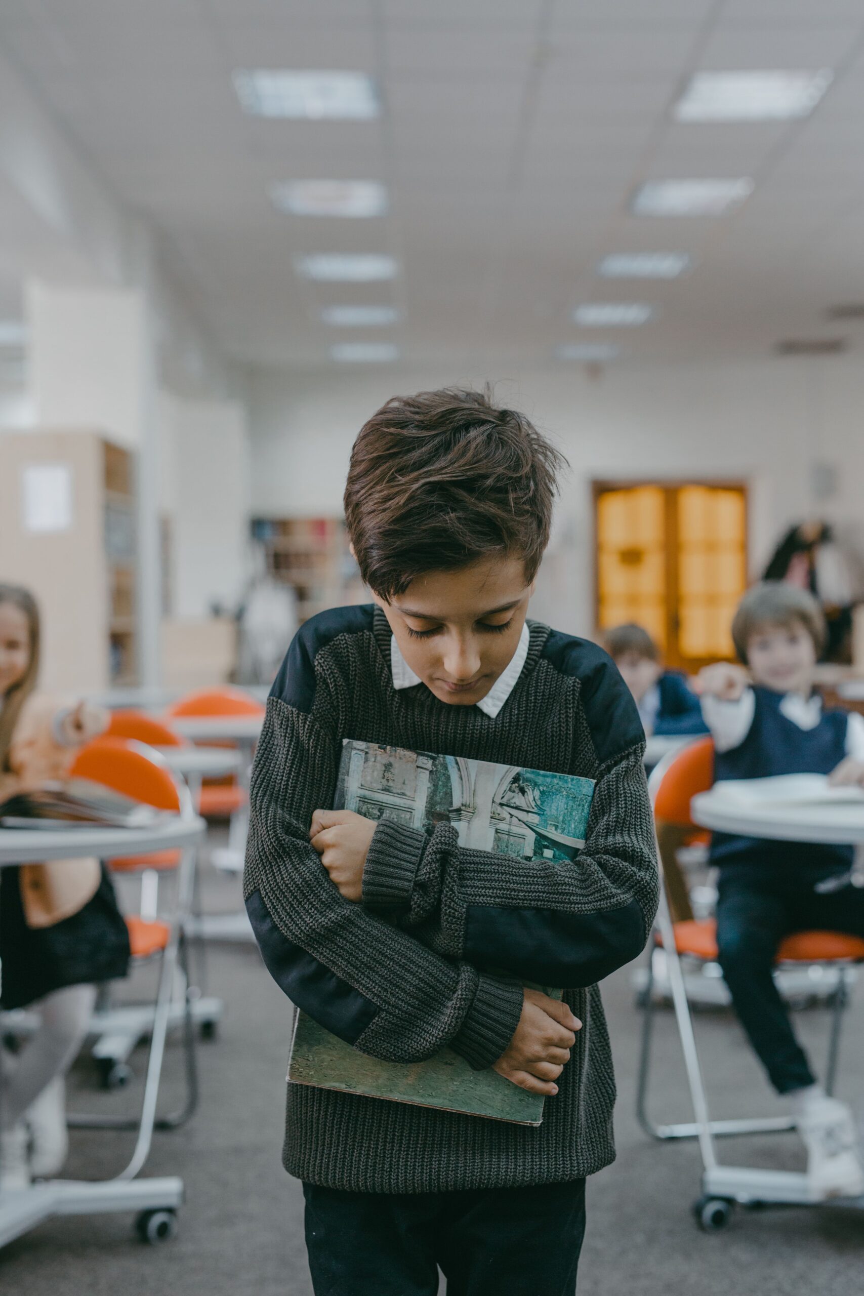Garçon timide serrant un livre contre lui en classe